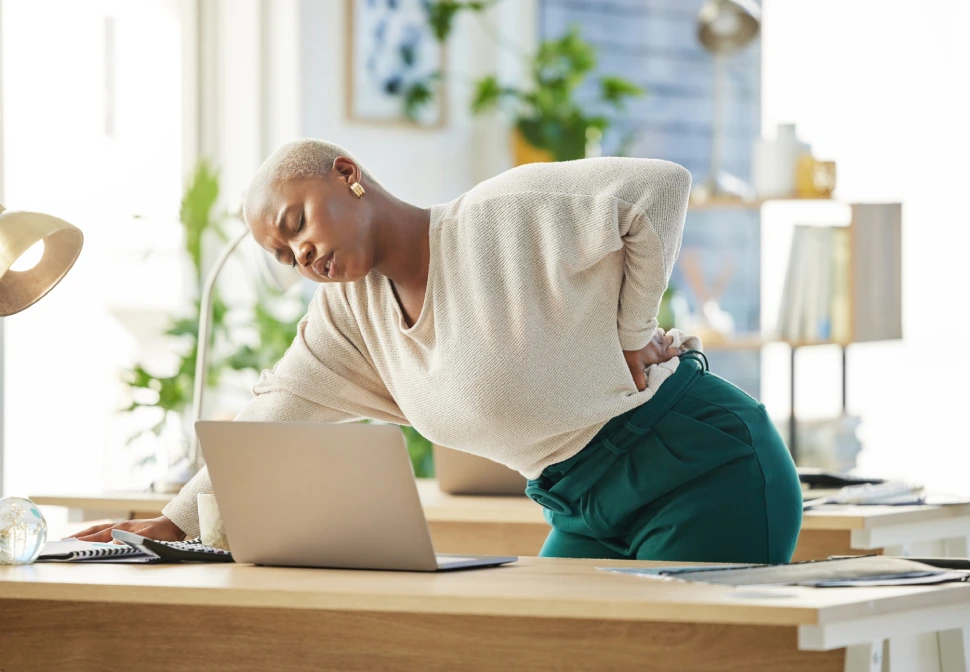 Pessoa com a mão na região lombar esquerda indicando ponto de dor localizada, ilustrando possíveis causas como contratura ou hérnia de disco.