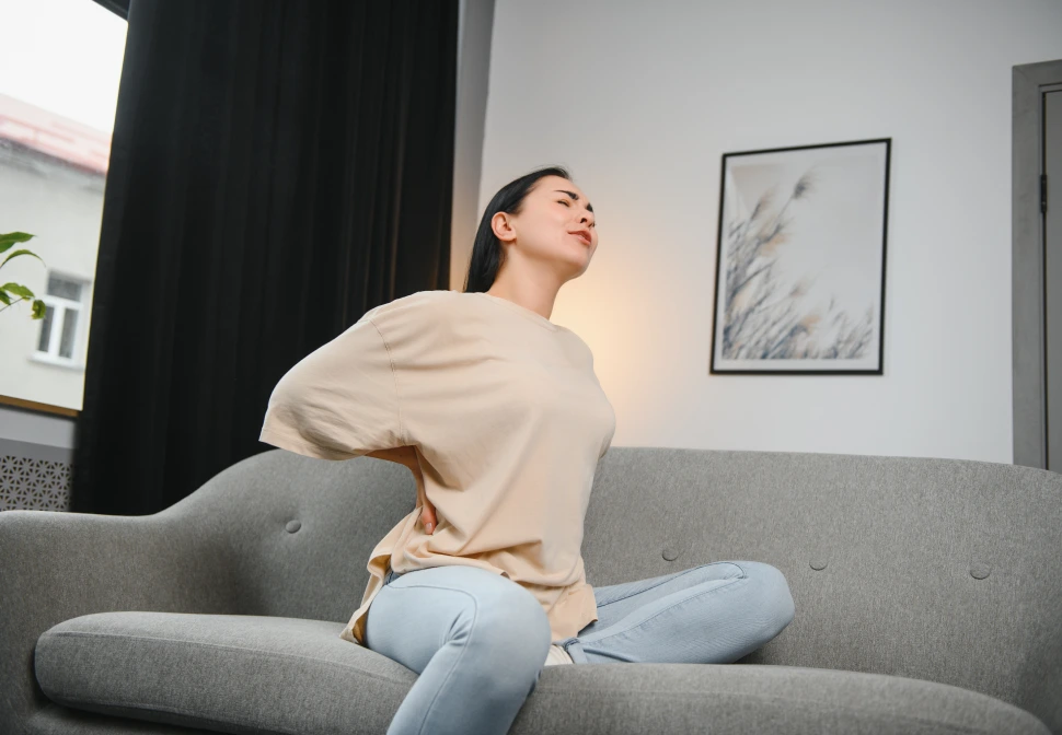 Pessoa com a mão nas costas demonstrando desconforto ao tentar respirar fundo, ilustrando possíveis dores na coluna torácica ou contraturas musculares.